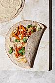 A hummus, carrot and chicken breast wrap