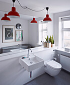 White bathroom with mirrored wall and red pendant lights