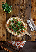 Pizza with ham and fresh tomatoes garnished with rucola