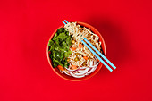 Bowl with noodles, onion, carrot slices and fresh parsley
