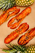 Lobsters with shells and claws near whole fresh pineapples