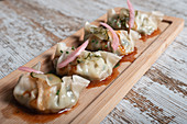 Traditional Japanese boiled gyoza dumplings served with sauce on wooden board