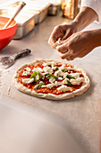 Mozzarella being added to a Pizza Margherita