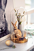 Gold-coloured Easter bunny and posy of flowers under glass cover