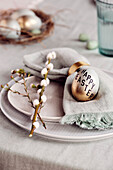 Gold-coloured Easter egg with 'Happy Easter' motto decorating plate