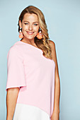 A blonde woman wearing a pink, one-shoulder top