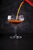Schaum aus der Mokka-Kanne zu einem Kaffeecocktail in ein Glas gießen