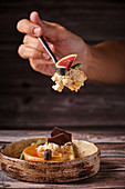 Hand with spoon of caramel cheesecake and piece of fig