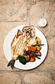 A whole fried bass with coriander mayonnaise and vegetables