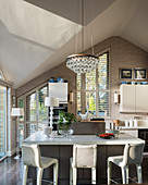 Barstools at island counter in modern, light-flooded kitchen