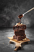 Stack of brownie with nuts and pouring chocolate sauce