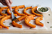 Hand with fork smashing baked pumpkin slices