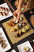 Hand with chopsticks taking assorted veggie sushi