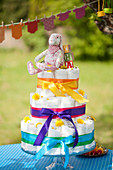 Diaper cake with ribbons in rainbow colors and onesie garland for a baby shower