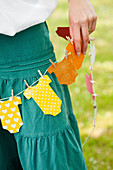 Woman holding homemade garland with onesies made of colored paper