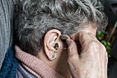 Elderly woman holding hearing aid