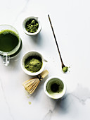 Three cups of Matcha tea and powder with whisk