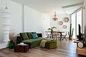 Old wooden chest as side table and green upholstered furniture in open living room