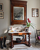 Antique wood and marble washstand below wall-mounted mirror