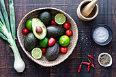 Zutaten für Guacamole (Avocado, Limetten, Tomaten, Frühlingszwiebel und Gewürze)