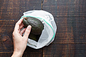 Hand nimmt Avocado aus Stoffsack