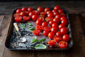 Kirschtomaten mit grobem Salz und Basilikum auf Ofenblech