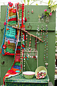 Colourful crocheted scarf and necklaces hung on green wooden door