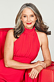 A grey-haired woman wearing a festive, red, halter-neck dress