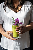 Frau hält Glas mit grünem Matcha-Getränk
