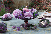 Tischdekoration mit Kerze, Deko-Chrysanthemen, Knospenheide Kugel und Kränzchen, Beeren vom Liebesperlenstrauch und Strauchveronika