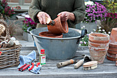 Scissors, small tools, for cleaning pots woman scrubs clay pot in a tub with water