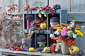 Colorful autumn decoration with bouquet of chrysanthemums, roses, snowberries, Chinese lanterns and peacocks, apples, ornamental apples, quinces, balls of heather in clay pots