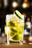 Cocktail mit Crushed Ice und Limettenstücken im Glas