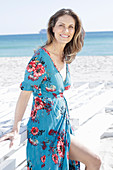 A long-haired woman on the beach wearing a summer dress