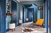 Yellow easy chair and row of houseplants in blue hallway