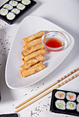 Spring rolls with dipping sauce and sushi