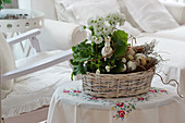 Basket with primrose, horned violets, and branches as an Easter decoration with an Easter bunny and Easter eggs