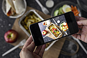 Foto von Nudelgericht und Salat zum Mitnehmen auf dem Smartphone