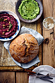 A pea dip and a beetroot dip next to a loaf of sourdough bread