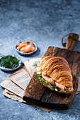 Croissant with salmon and dill on wooden board