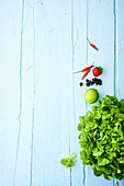 Grüner Blattsalat und Früchte auf hellblauer Holzfläche