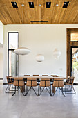 Modern upholstered chairs around large table in dining area with high ceiling