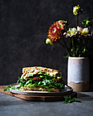 Vegan sandwich filled with hummus, avocado, sundried tomatoes and rocket salad