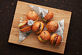 Mini hamburgers on skewers on wooden board