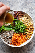 Putting dressing to gluten-free salad bowl with quinoa and raisins