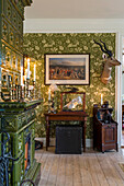 Tiled stove and antiques in room with green wallpaper