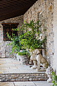 Stone dog next to amphora on the terrace of stone cottage
