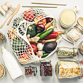 Obst und Gemüse im Einkaufsnetz und verschiedene Vorratsgläser mit Lebensmitteln