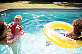 Mother and daughters playing in summer swimming pool