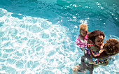 Mother and daughters in sunny summer swimming pool